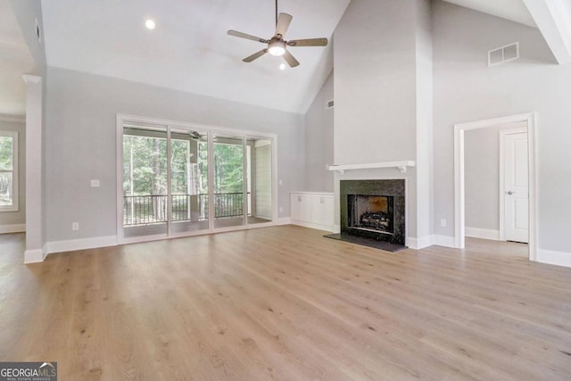 unfurnished living room with ceiling fan, a fireplace, high vaulted ceiling, and light wood-type flooring