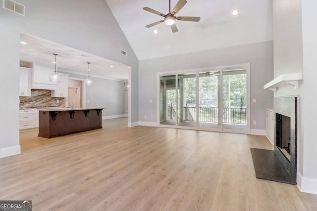 living room featuring ceiling fan, sink, light hardwood / wood-style floors, and high vaulted ceiling