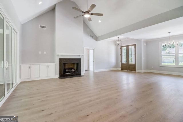 unfurnished living room featuring ceiling fan with notable chandelier, high vaulted ceiling, french doors, and light wood-type flooring