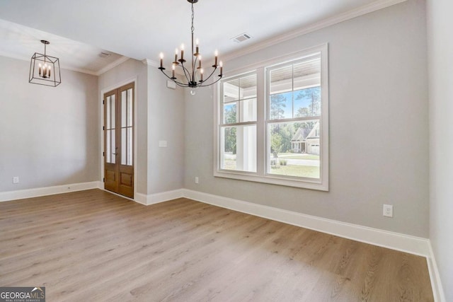 unfurnished dining area featuring crown molding, light hardwood / wood-style floors, and a chandelier