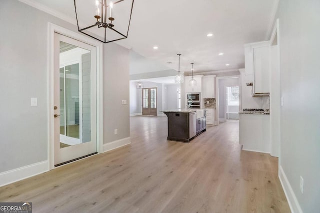 kitchen with white cabinetry, decorative light fixtures, a kitchen island with sink, and a wealth of natural light