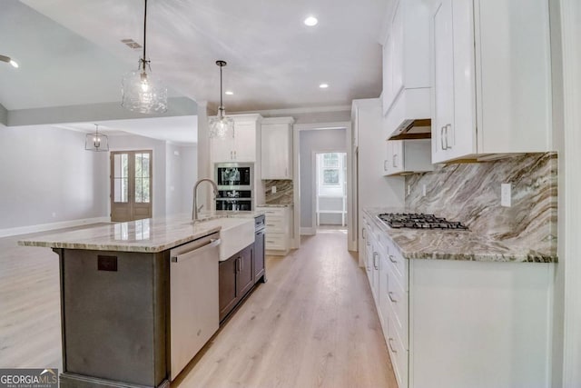 kitchen with hanging light fixtures, white cabinets, backsplash, and a spacious island