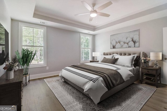 bedroom with a raised ceiling, ceiling fan, and multiple windows