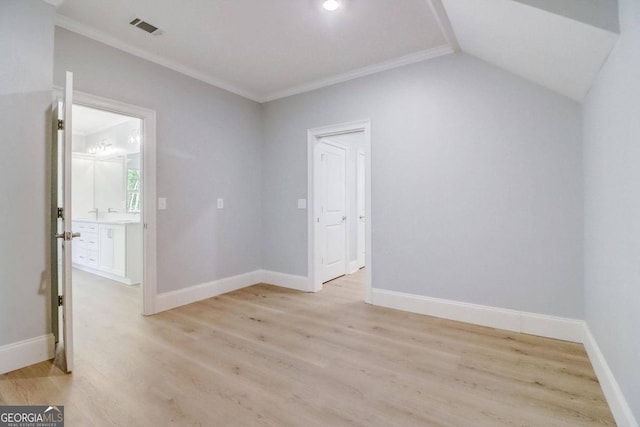 empty room with vaulted ceiling, crown molding, and light hardwood / wood-style floors