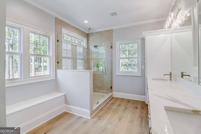 bathroom with vanity, crown molding, wood-type flooring, and a shower with door