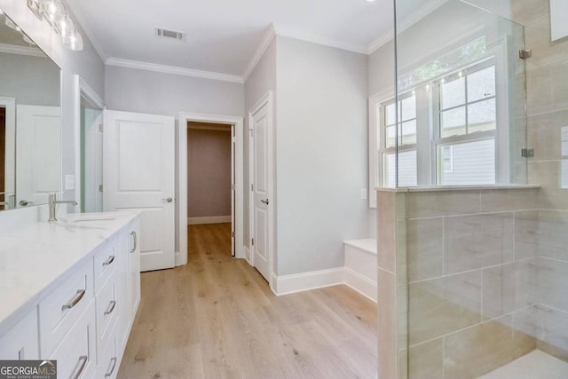 bathroom featuring vanity, hardwood / wood-style flooring, ornamental molding, and walk in shower