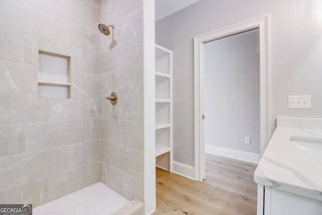 bathroom with hardwood / wood-style flooring, vanity, and a tile shower