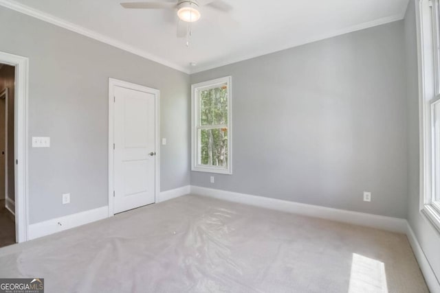 spare room featuring light carpet, ornamental molding, and ceiling fan