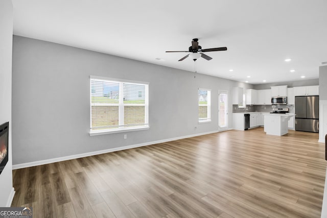 unfurnished living room with light hardwood / wood-style flooring and ceiling fan