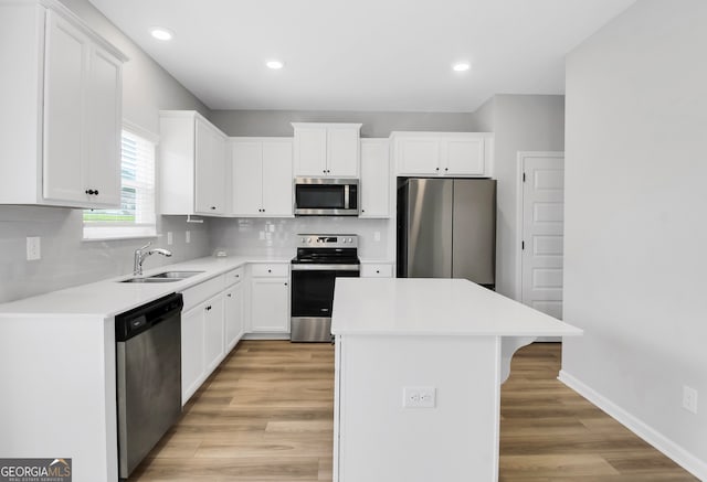 kitchen featuring a kitchen island, light hardwood / wood-style flooring, sink, white cabinetry, and appliances with stainless steel finishes