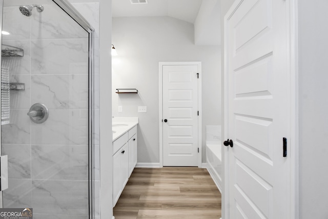 bathroom featuring vanity, lofted ceiling, hardwood / wood-style floors, and plus walk in shower