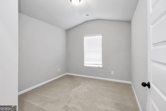 spare room with vaulted ceiling and light colored carpet