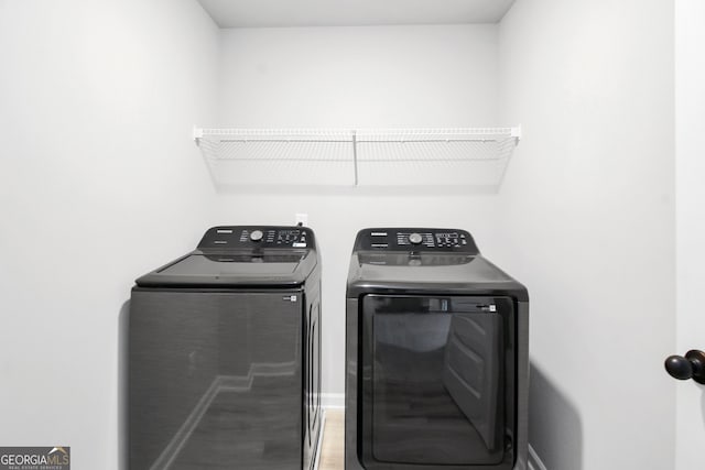 clothes washing area featuring hardwood / wood-style floors and washing machine and clothes dryer