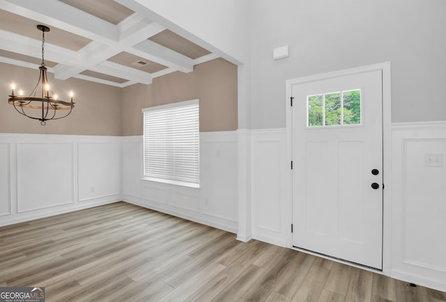 entrance foyer with beam ceiling, coffered ceiling, light hardwood / wood-style flooring, and a chandelier