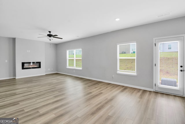 unfurnished living room with a healthy amount of sunlight, light wood-type flooring, and ceiling fan