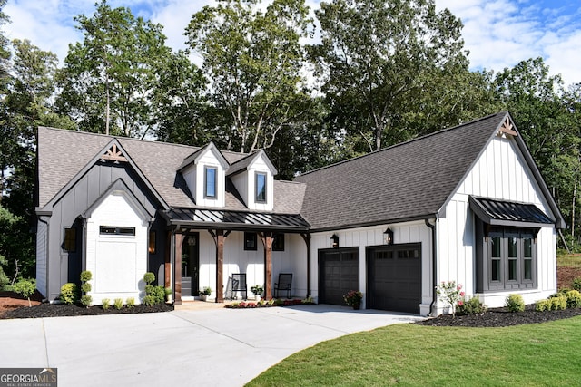 modern farmhouse featuring a front yard, covered porch, and a garage