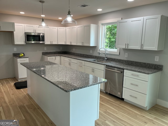 kitchen with white cabinetry, sink, light hardwood / wood-style floors, a kitchen island, and appliances with stainless steel finishes