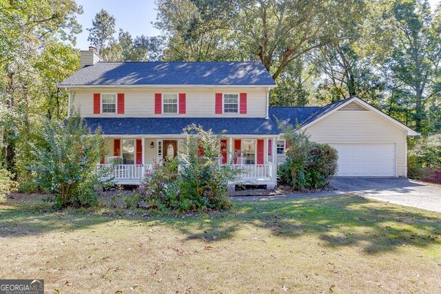 view of front of property featuring a front yard, a porch, and a garage