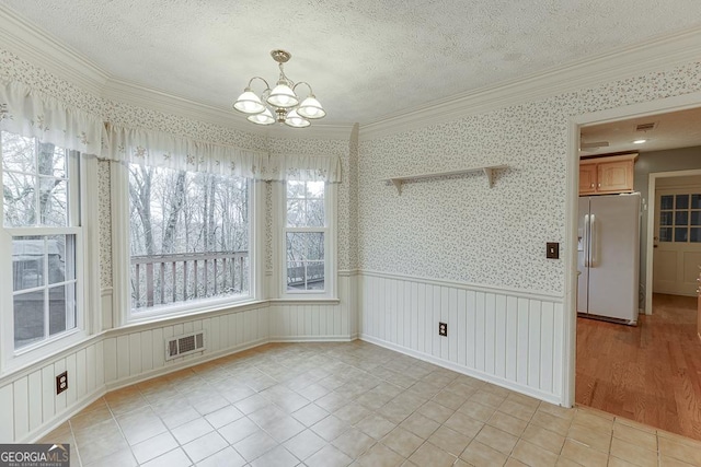 unfurnished dining area with wainscoting, light tile patterned floors, a textured ceiling, a notable chandelier, and wallpapered walls