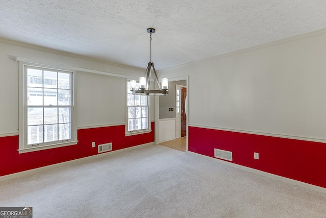 empty room with a textured ceiling, light carpet, a notable chandelier, and visible vents