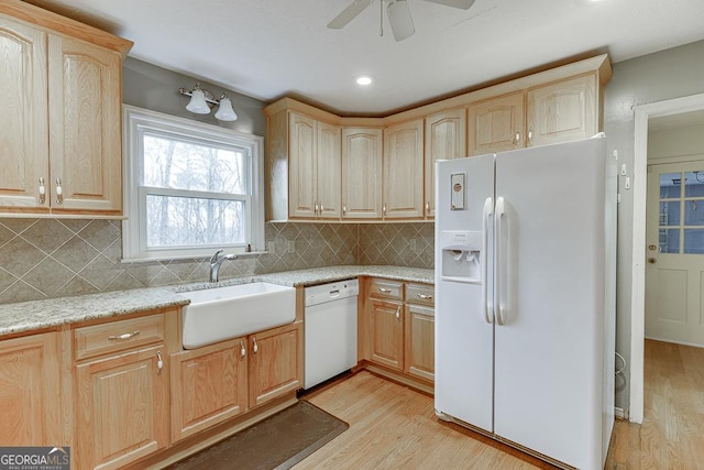 kitchen with light wood-type flooring, light brown cabinetry, light stone counters, white appliances, and a sink