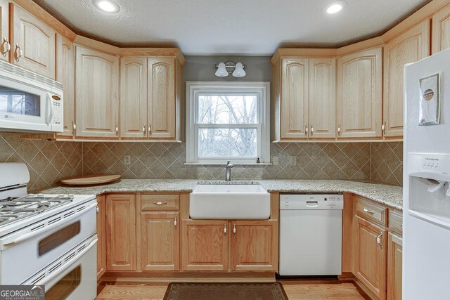 kitchen with light hardwood / wood-style floors, a textured ceiling, sink, and white appliances