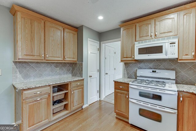 kitchen with white appliances, light stone counters, light wood-type flooring, and light brown cabinets