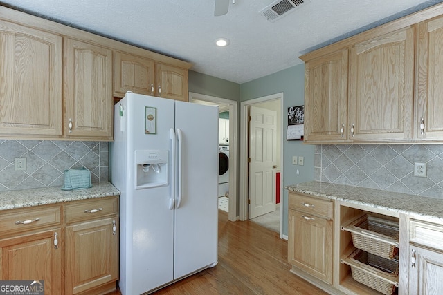 kitchen featuring light stone countertops, decorative backsplash, light hardwood / wood-style flooring, and white fridge with ice dispenser