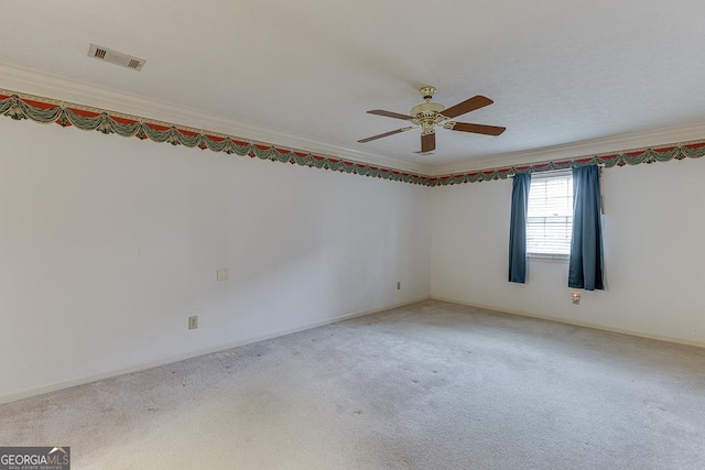 empty room with ceiling fan, visible vents, carpet floors, and ornamental molding