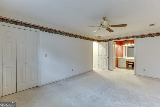 unfurnished bedroom featuring crown molding, ensuite bathroom, baseboards, and visible vents