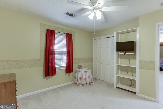 interior space featuring a textured ceiling, light colored carpet, and ceiling fan