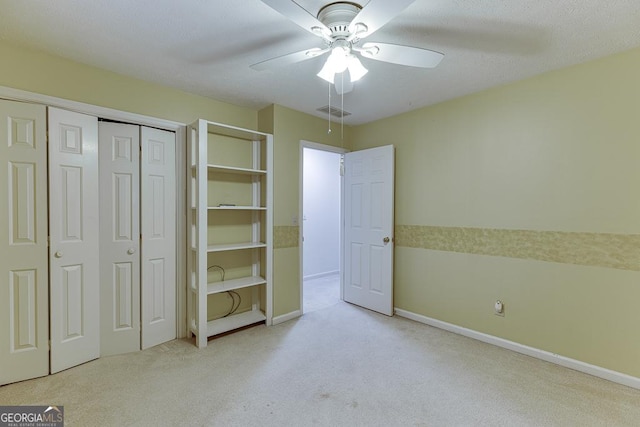 unfurnished bedroom featuring light colored carpet, baseboards, visible vents, ceiling fan, and a closet