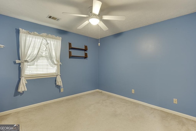 empty room with baseboards, a ceiling fan, light colored carpet, and visible vents