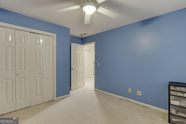 bedroom with ceiling fan, light carpet, a closet, and baseboards