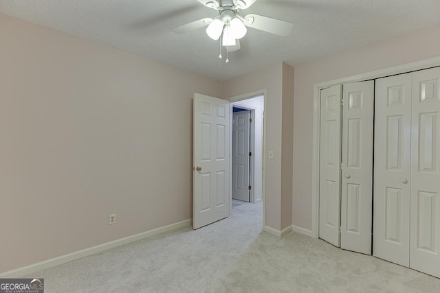 unfurnished bedroom featuring a ceiling fan, light carpet, a closet, and baseboards