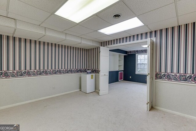 living area featuring a paneled ceiling and carpet flooring