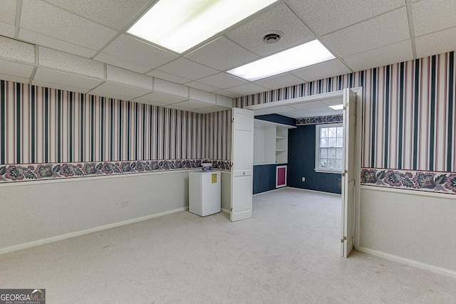 empty room featuring carpet, visible vents, a paneled ceiling, and baseboards