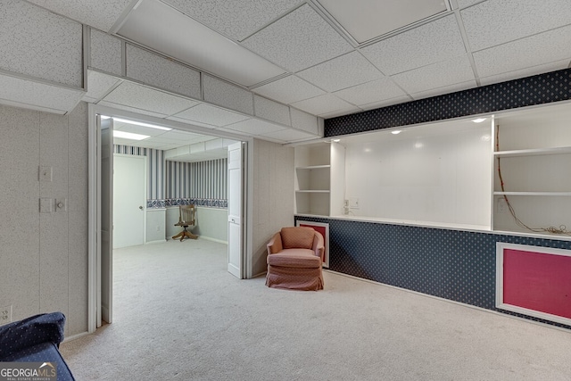 living area with a paneled ceiling and carpet flooring