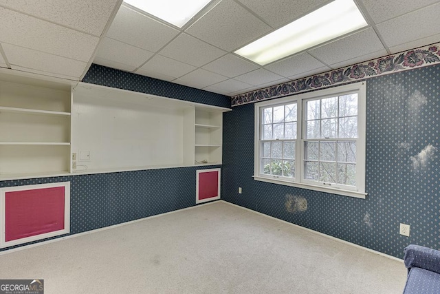 unfurnished room featuring wallpapered walls, baseboards, a paneled ceiling, and carpet flooring