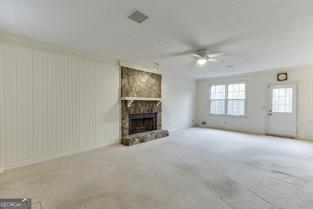 unfurnished living room with a fireplace, light carpet, a textured ceiling, crown molding, and a ceiling fan