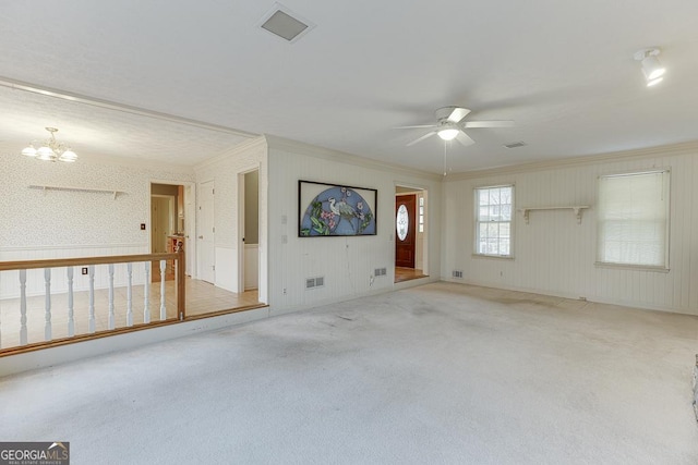 spare room with ceiling fan with notable chandelier, ornamental molding, light carpet, and visible vents