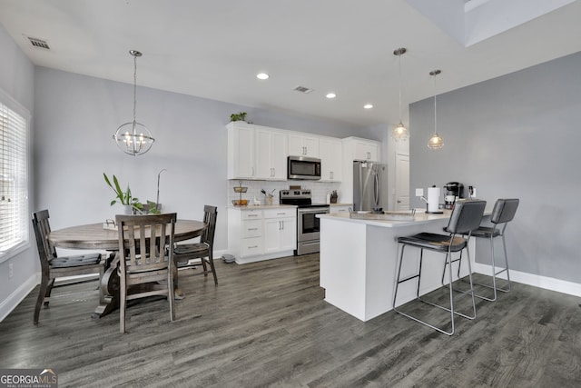 kitchen with dark hardwood / wood-style floors, stainless steel appliances, backsplash, decorative light fixtures, and white cabinetry