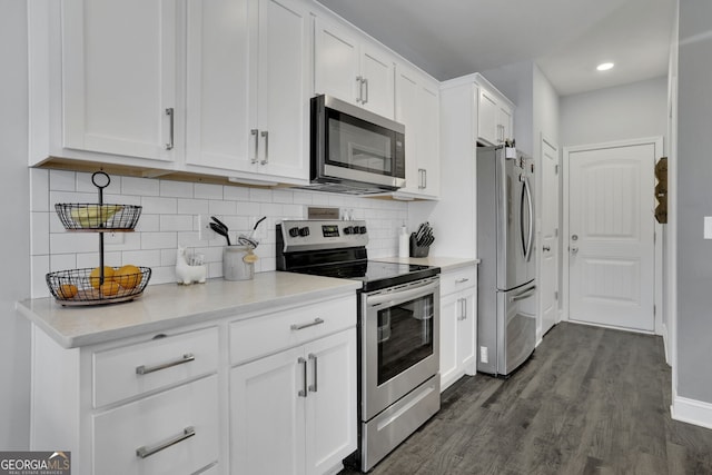 kitchen with appliances with stainless steel finishes, white cabinets, backsplash, and dark hardwood / wood-style flooring