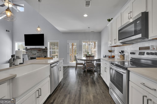 kitchen featuring appliances with stainless steel finishes, backsplash, dark hardwood / wood-style flooring, white cabinetry, and pendant lighting