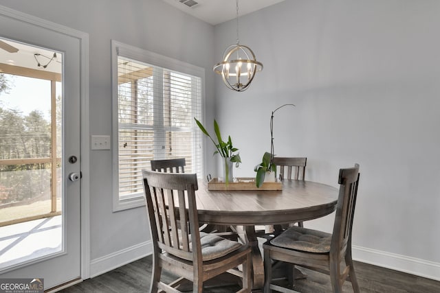 dining space with dark hardwood / wood-style floors, a healthy amount of sunlight, and a chandelier