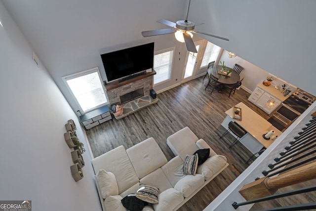 living room featuring ceiling fan, a towering ceiling, dark hardwood / wood-style flooring, and plenty of natural light