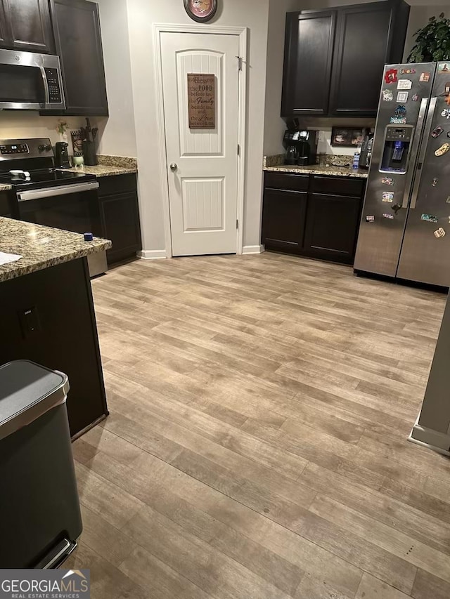 kitchen with stainless steel appliances, light wood-style flooring, baseboards, and light stone countertops