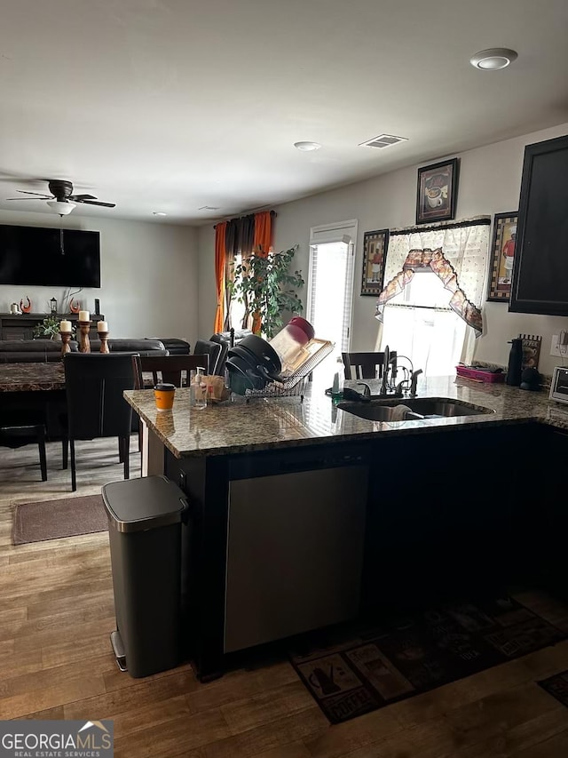 kitchen with visible vents, dark stone counters, a ceiling fan, wood finished floors, and a sink