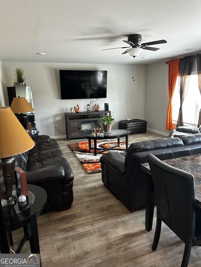 living area with a ceiling fan, baseboards, and wood finished floors