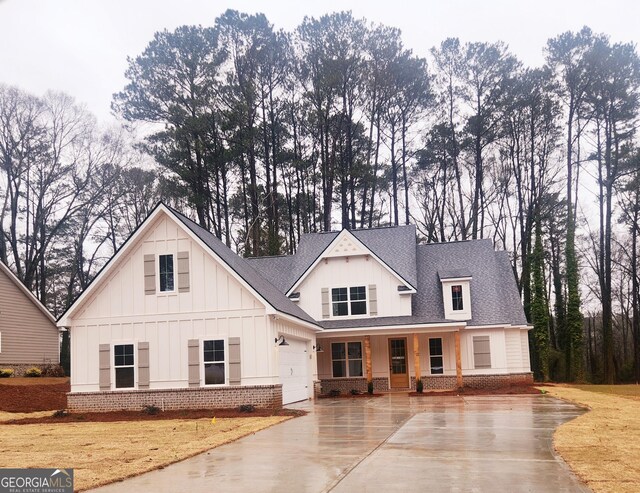 modern inspired farmhouse with driveway, board and batten siding, a shingled roof, a garage, and brick siding